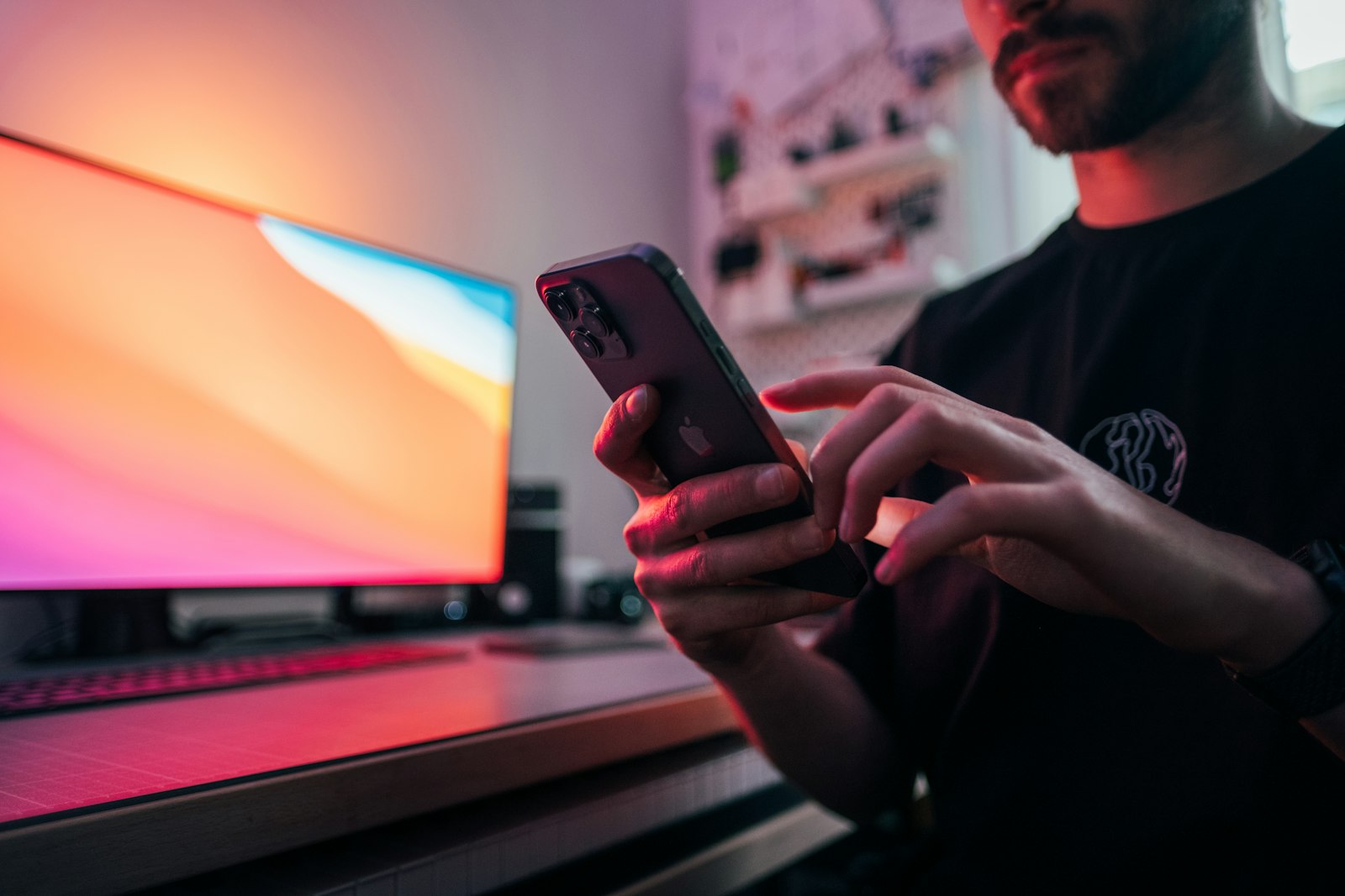 Man holding a smartphone and browsing apps next to a laptop