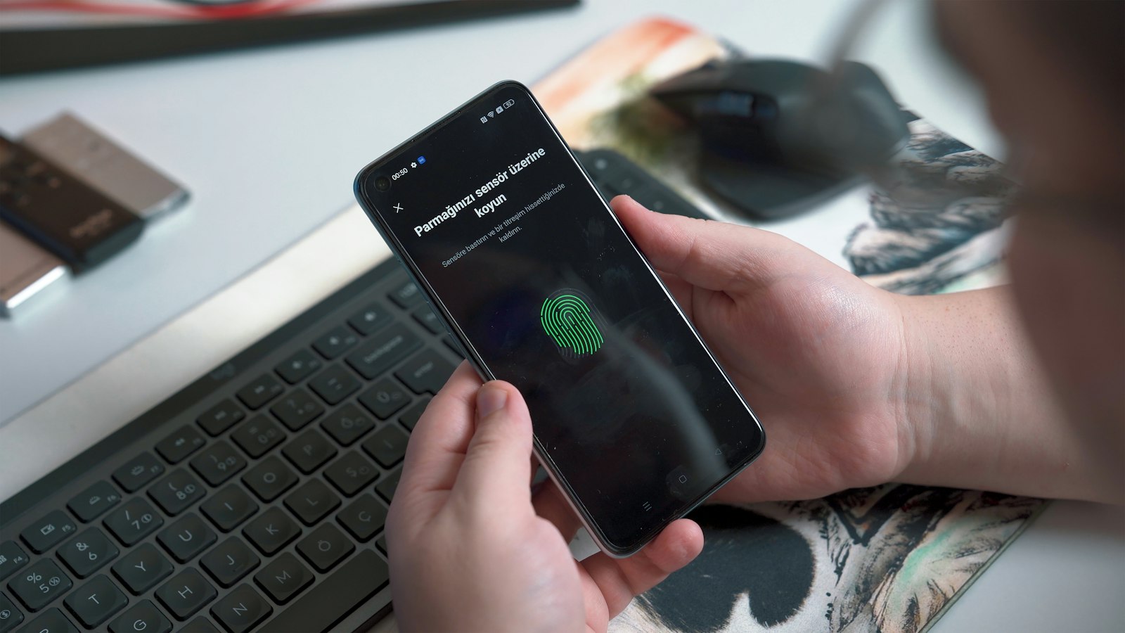 Person holding a smartphone showing a fingerprint authentication prompt