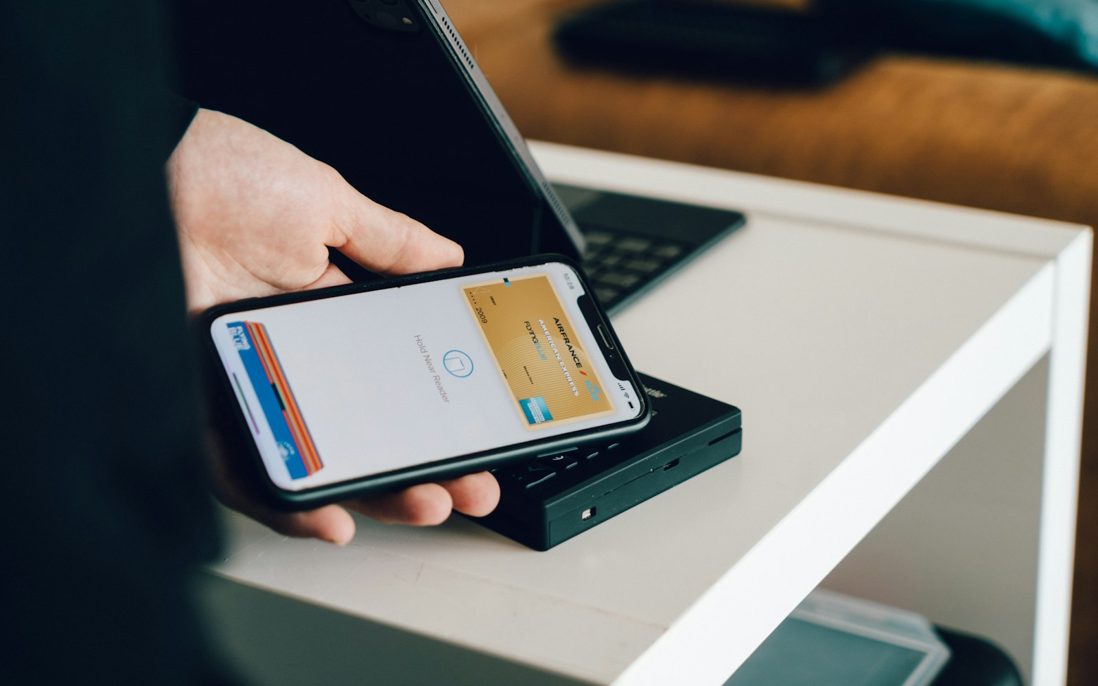 Person holding a smartphone over a card reader to pay with a digital wallet
